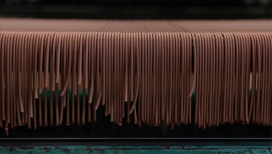 Rows of freshly made natural incense sticks hanging to dry on a wooden rack