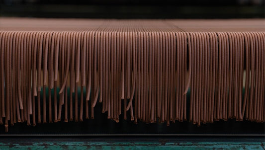 Rows of freshly made natural incense sticks hanging to dry on a wooden rack