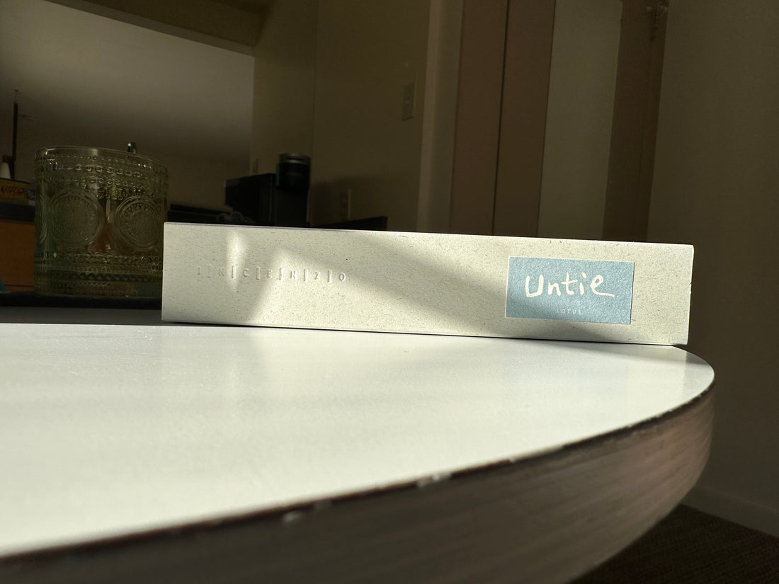 A box of INCENZO Untie lotus incense on the edge of a round white table in low evening light