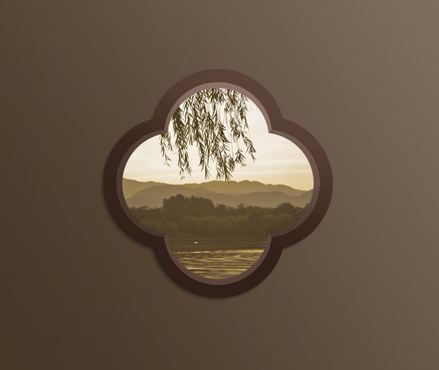 A quatrefoil garden window set into a courtyard wall, framing willow branches, a lake and distant hills at dusk