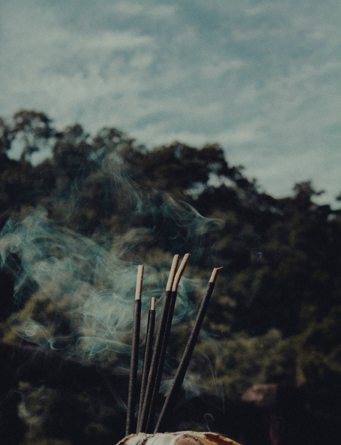 Incense sticks burning against a misty mountain landscape