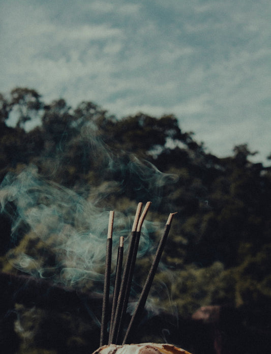 Incense sticks burning against a misty mountain landscape