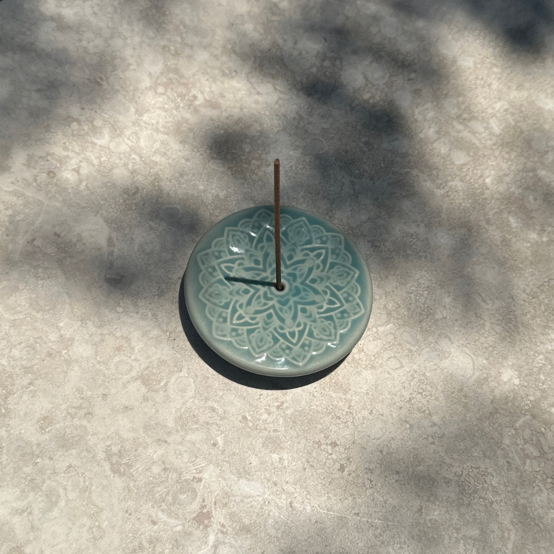 Blooming Lotus Incense Disc on stone surface with dappled natural light