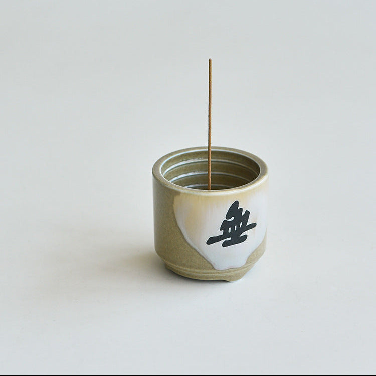 Handmade ceramic incense holder with a single incense stick burning for good fortune
