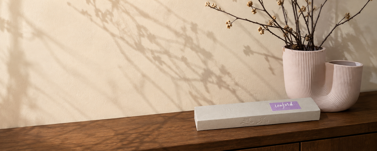 Unfold orchid incense on walnut beside a blush ceramic vase in warm afternoon light