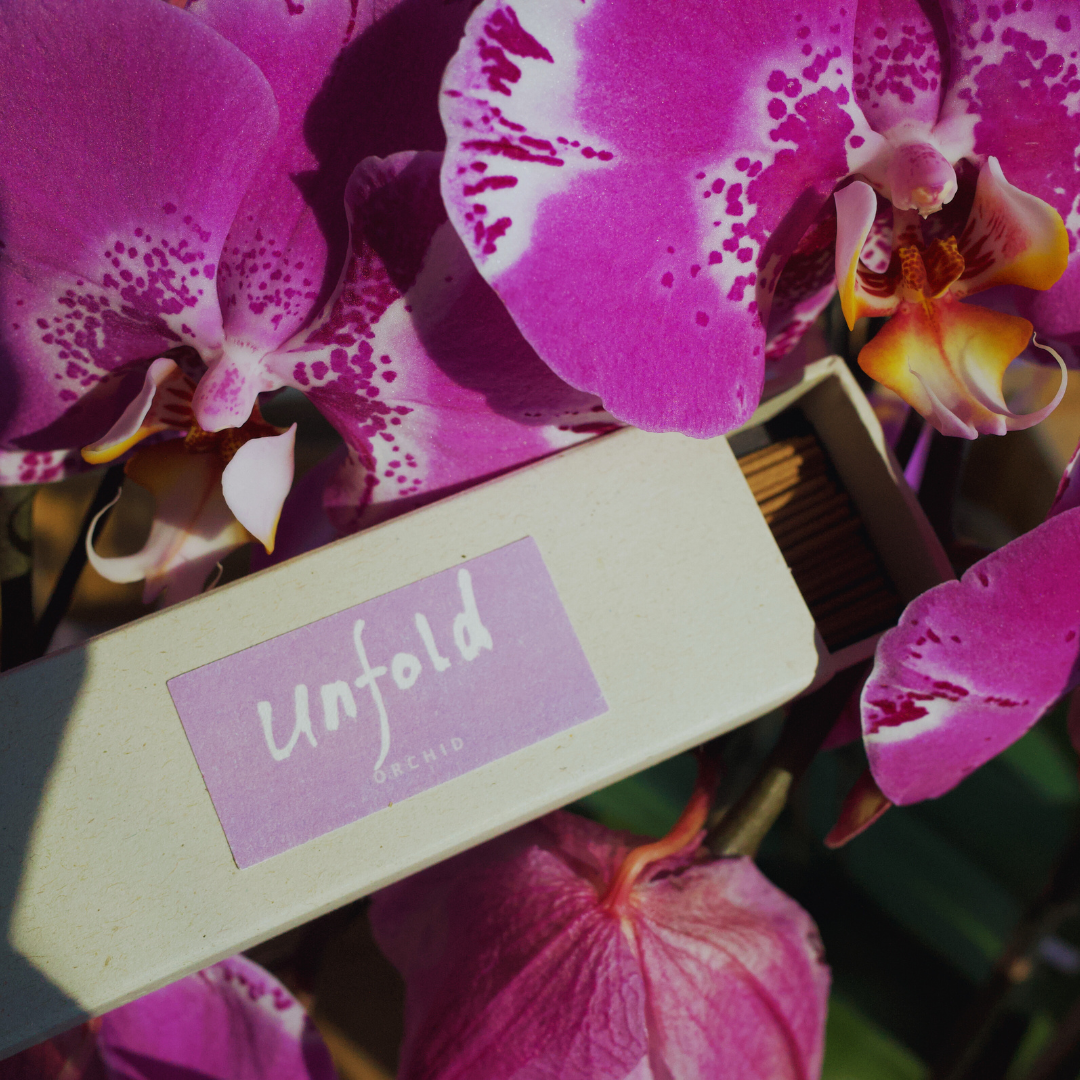 Pink orchids with a 'Unfold' incense box