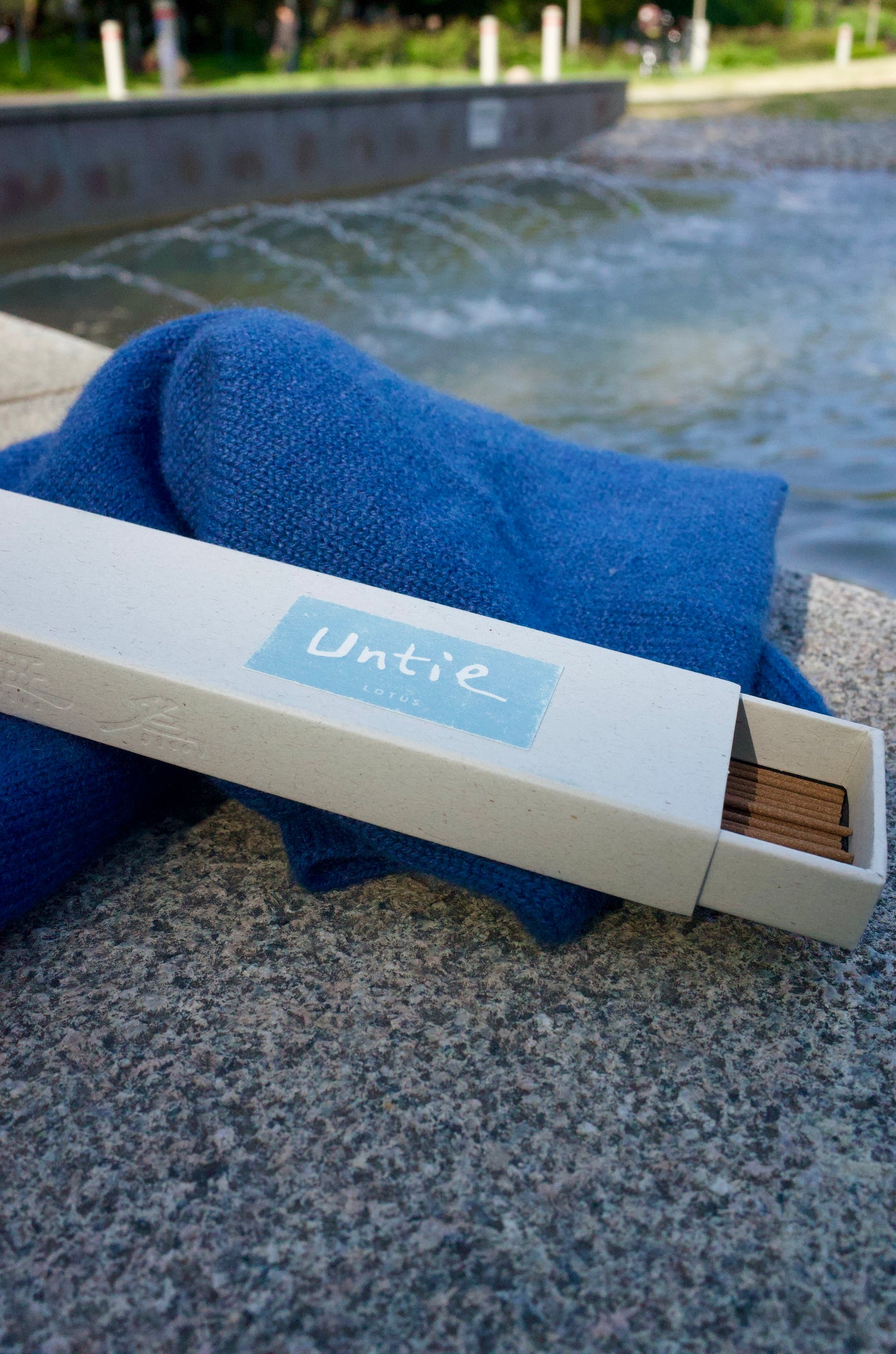Untie Lotus incense box beside water and blue fabric